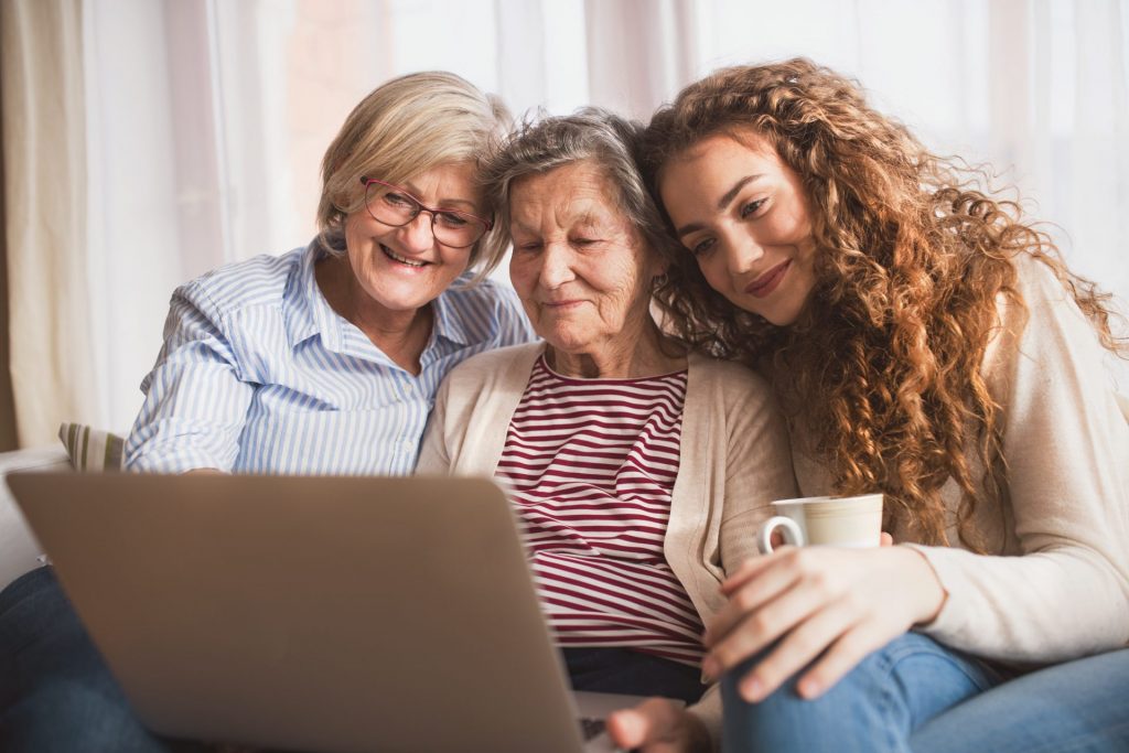 a teenage girl, mother and grandmother looking at a laptop at home
