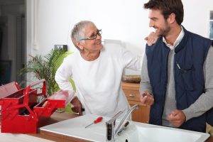 male carer providing respite care service to an elderly woman, with a toolbox next to the sink