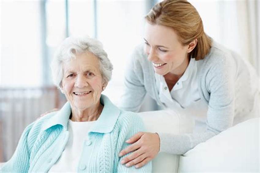 A female carer holds the shoulders of a happy elderly woman